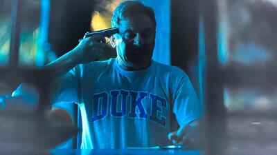 White Lotus dad with Duke shirt and gun